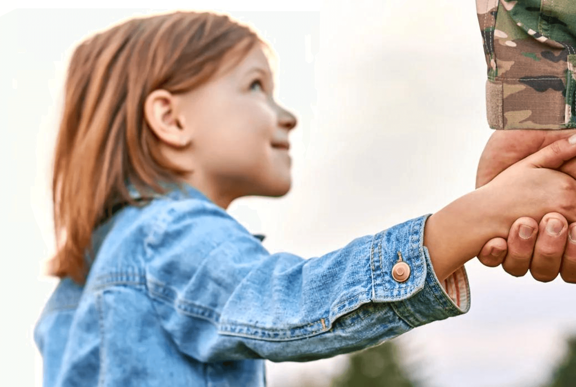 A child reaching out to take her military parent's hand